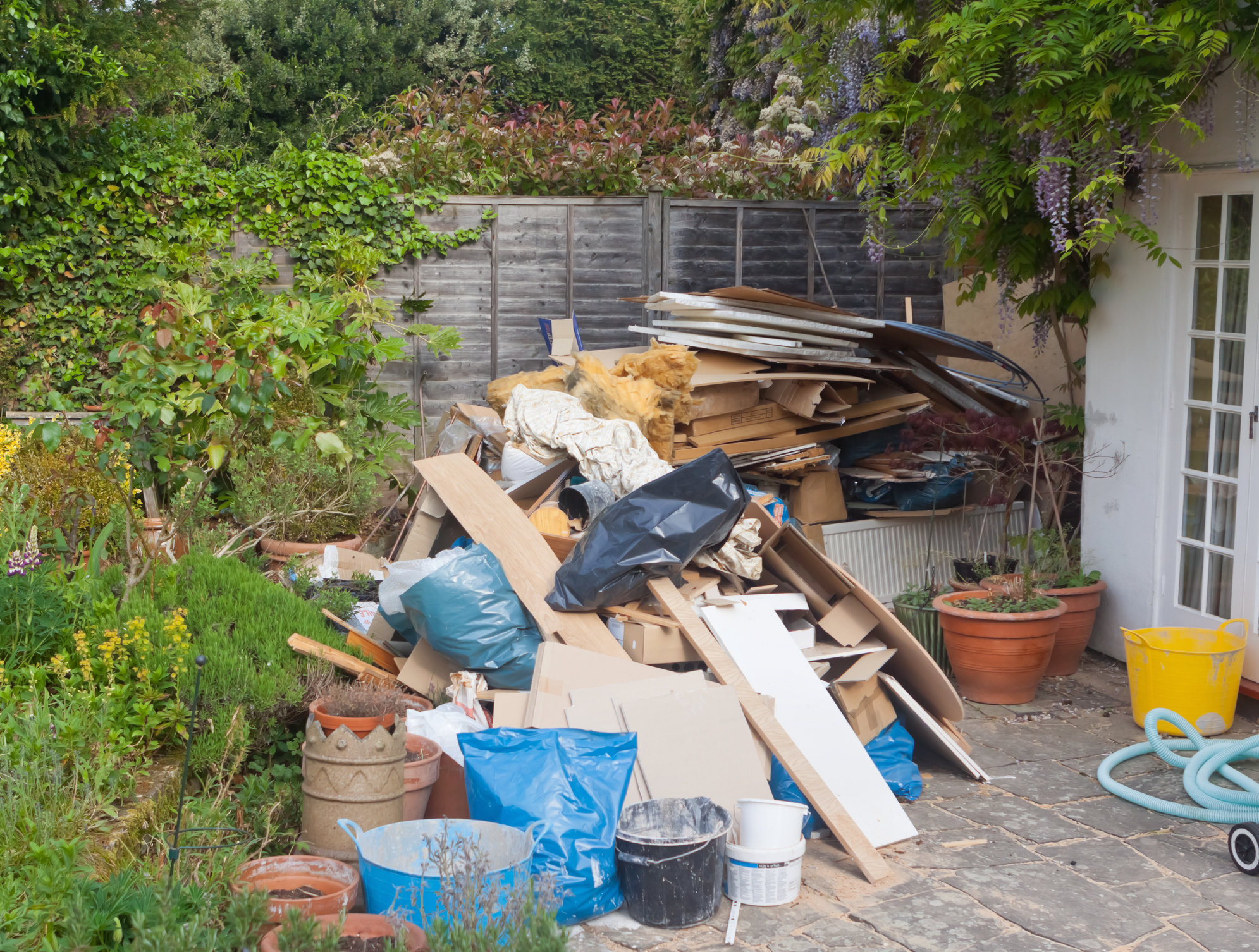 a pile of junk at a residence waiting to be removed and sorted as part of an eco-friendly junk removal service by Go Green Landscape Supply.